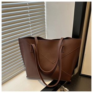 Detail shot of a dark brown large tote bag with geometric layered stitching on a windowsill