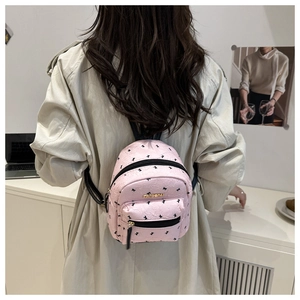 Pink printed mini backpack with gold fashion logo on woman shoulder back view