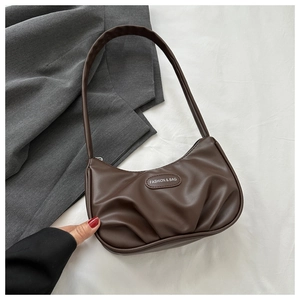Détail d'un sac sous le bras plissé marron foncé avec une étiquette en cuir