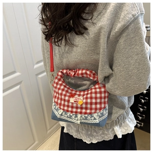 Detail of red gingham and denim bucket bag with lace trim and cherry patch on model