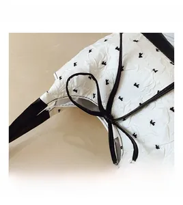 Detail shot of white wrinkled texture fabric with black rabbit patterns and leather trim
