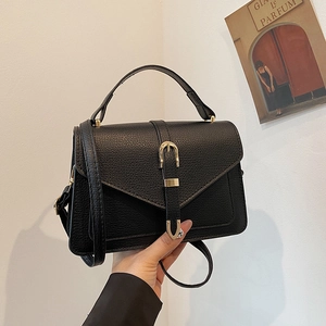 Elegant black lychee textured handbag with gold horseshoe clasp and adjustable strap