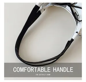 Close-up of smooth black handles on a white pleated polka dot tote bag surface