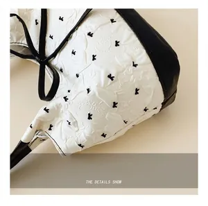 Detail showing white pleated fabric with black letter embroidery and leather handle edges