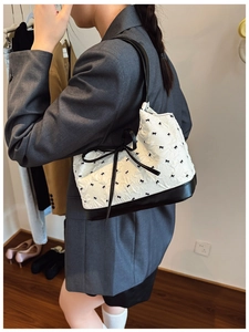 Fashion model wearing a stylish white hobo bag with black bow pattern and crinkled texture