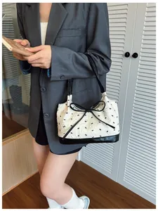 Detail of white embossed bow bag with black embroidery and premium leather accents