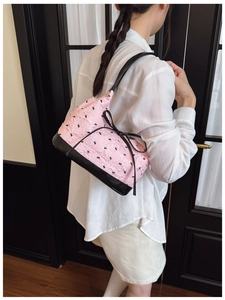 Detailed view of pink quilted handbag featuring black rabbit prints and bow decoration