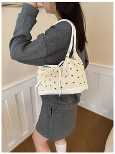 Détail du sac à bandoulière crème avec broderie de nœuds noirs et tissu plissé