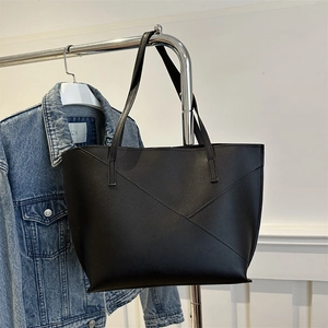 Minimalist black tote bag with geometric stitching hanging on a metal rack