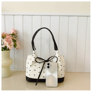 Detail of cream pleated tote bag with black bow patterns and leather-feel handles