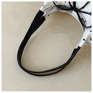 Detailed close-up of seersucker handbag with black bow patterns and leather handles