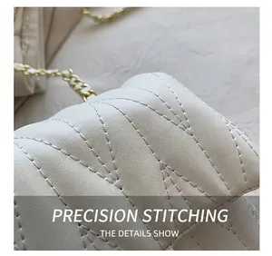 Detailed macro view of white quilted faux leather bag with V-shaped stitching and gold chain