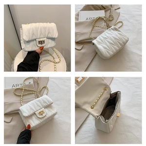 Detail of white V-quilted crossbody bag showing metal turn-lock and chain strap