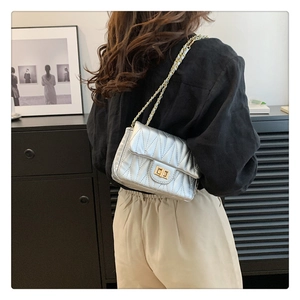 Detail of silver quilted crossbody bag featuring a golden chain strap and twist lock