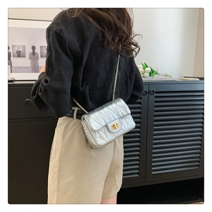 Detail of silver quilted crossbody bag with gold twist lock and chain strap on model