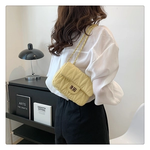 Pale yellow quilted crossbody bag with gold chain strap shown on model's shoulder