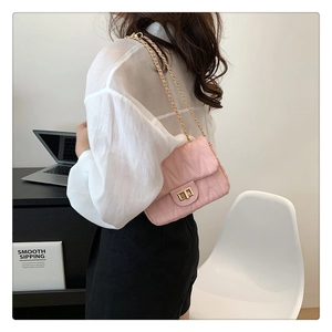 Pink quilted shoulder bag with gold chain strap and square twist lock on a minimalist model