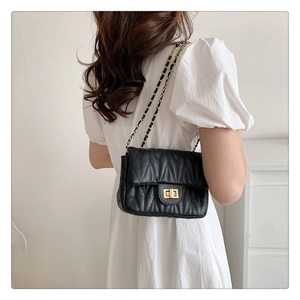 Close-up of black quilted leather shoulder bag featuring gold chain and square twist lock
