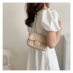 Beige quilted chain bag styled with a white dress in a minimalist interior setting