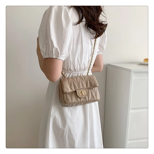 Detail of apricot quilted crossbody bag with gold chain strap and textured V-stitch