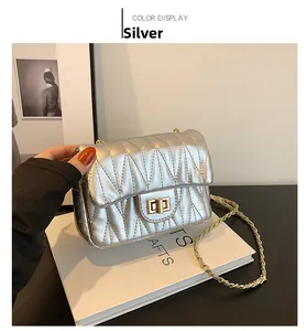 Detail view of silver quilted chain bag with V-shaped stitching and golden twist lock
