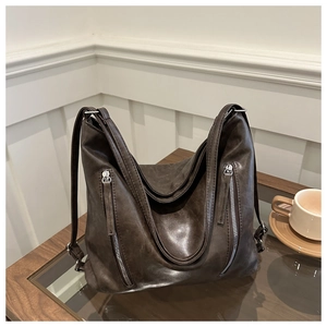 Detail of dark brown vintage leather shoulder bag featuring dual vertical front zippers