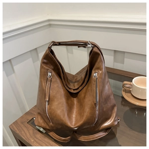 Detail of dark brown vintage leather backpack with dual silver zippers and top handle