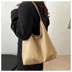 Detail of beige lychee textured leather hobo bag worn by model for commuter style