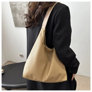 Detailed texture of khaki pebbled leather hobo bag with wide shoulder strap on model