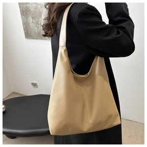 Side view of large cream boston tote bag in lychee pattern leather worn by model