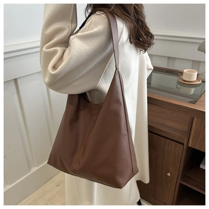 Close-up of a brown litchi grain leather hobo bag worn by a model in a cozy room