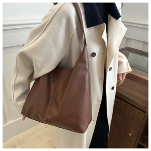Detailed close-up of brown pebbled leather hobo bag with minimalist design on a model