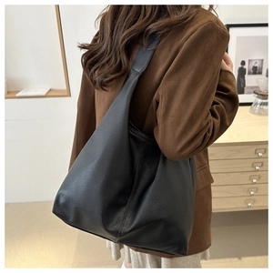 Close-up of black lychee grain leather hobo bag worn over the shoulder by a model