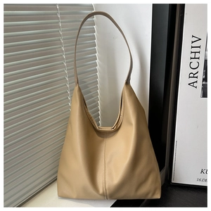 Close-up of beige lychee grain leather tote bag with vertical stitching and soft Hobo style