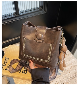 Detalle del bolso bombonera vintage marrón con bolsillo de remaches y correa tejida