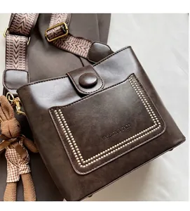 Detalle de bolso bucket marrón vintage con ribete de cuentas y correa tejida