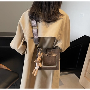 Bolso saco marrón con tachuelas, correa de jacquard y amuleto de conejo de peluche