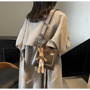 Bolso bandolera marrón vintage con correa tejida y colgante de conejo de peluche
