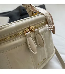 Close-up of golden dual zippers and smooth marble texture on a cylinder box bag