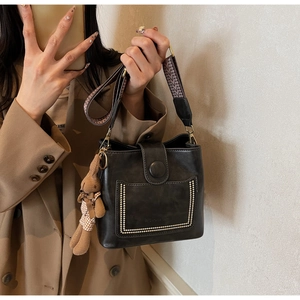 Detalle de bolso tipo cubo vintage en cuero negro con correa tejida de estilo étnico