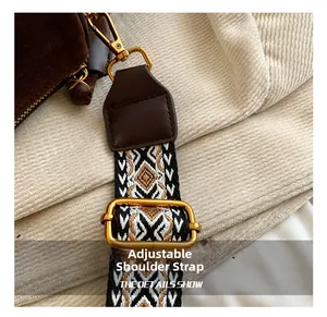 Detail of adjustable geometric jacquard strap and gold hardware on dark brown suede bag