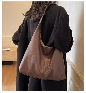 Detail einer dunkelbraunen Tote-Bag aus genarbtem Leder, getragen von einem Modell