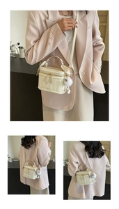 Detail of cream white box bag with silk scarf handle and plush ball charm on a model