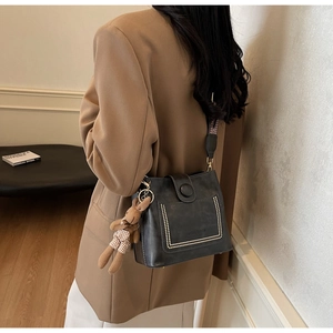 Detalle de bolso cubo de cuero negro con tachuelas, correa tejida y colgante de conejo