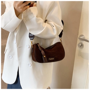 Detail of vintage brown suede shoulder bag with gold zipper and Fashion logo on model