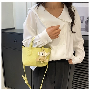 Close-up of yellow litchi pattern bucket bag with cute monkey charm on a model