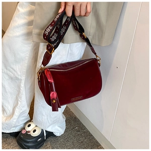 Detailed shot of dark red velvet pillow bag with geometric wide strap and metal plate