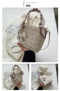 Close-up of beige crossbody bucket bag with horse carriage print and scarf handle