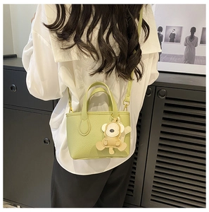 Rear view of a model wearing the mini green lychee leather bucket bag with animal charm