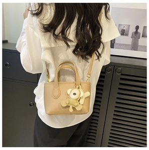 Khaki lychee leather handbag with a cute monkey charm shown from a side-wearing view